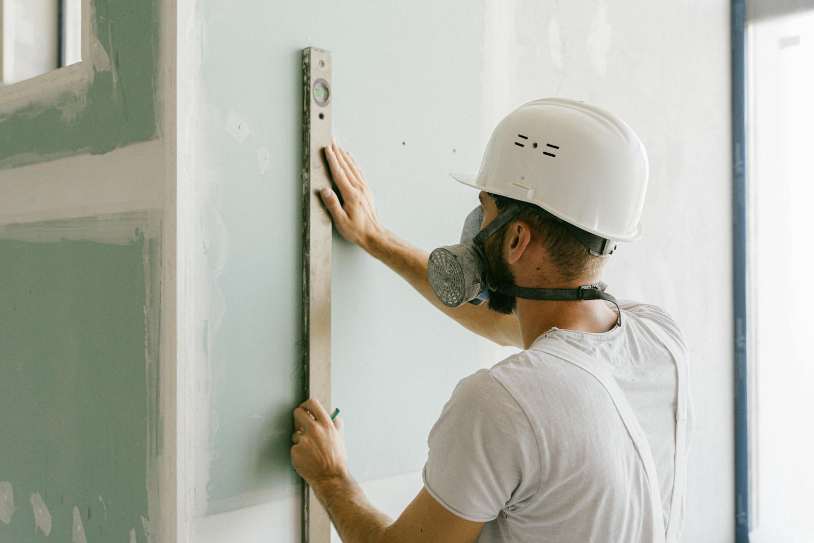 A construction worker using a leveler to ensure wall accuracy, showcasing precision.